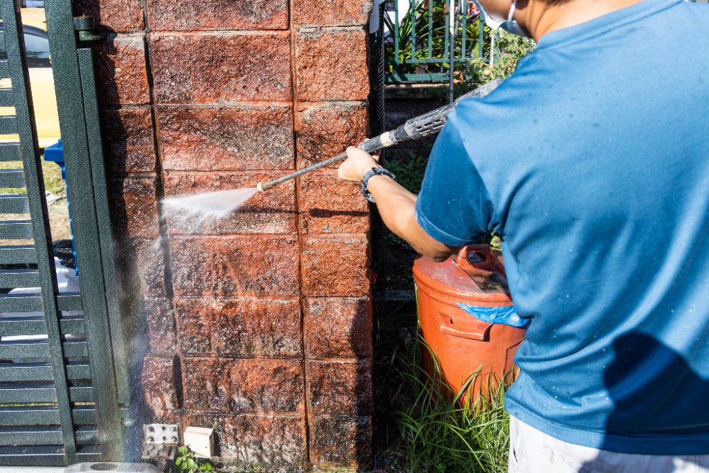 Worker pressure washing an exterior surface